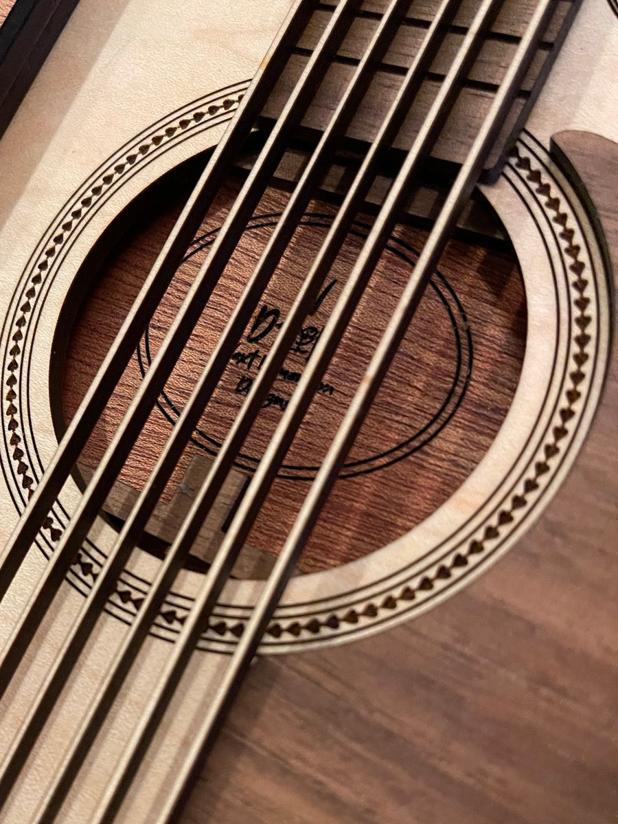 Close-up of a laser-cut layered wood guitar wall piece, strings over the sound hole