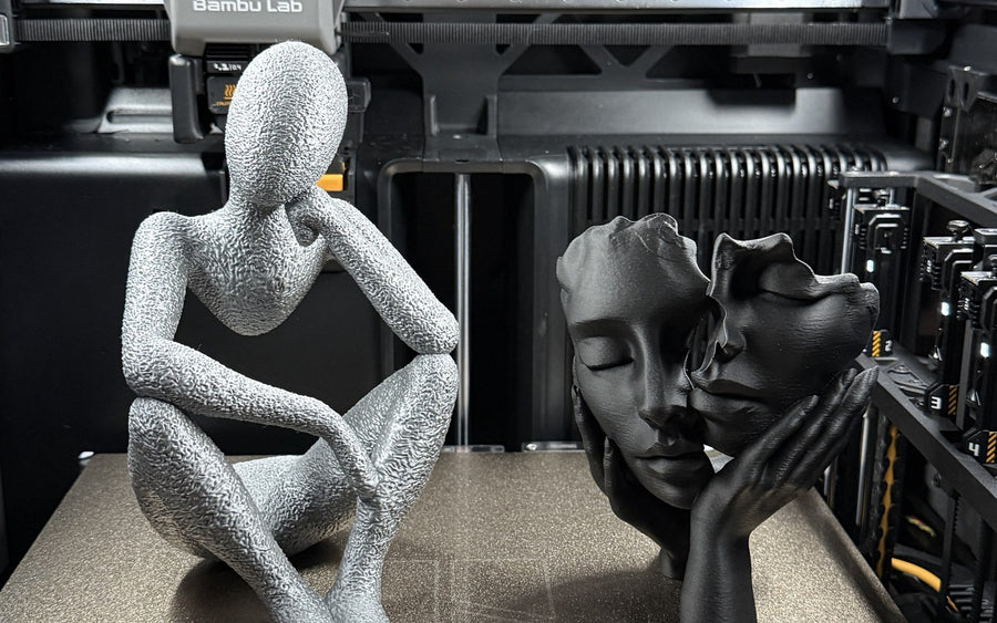 Two 3D-printed sculptures on the print bed of a Bambu Lab printer